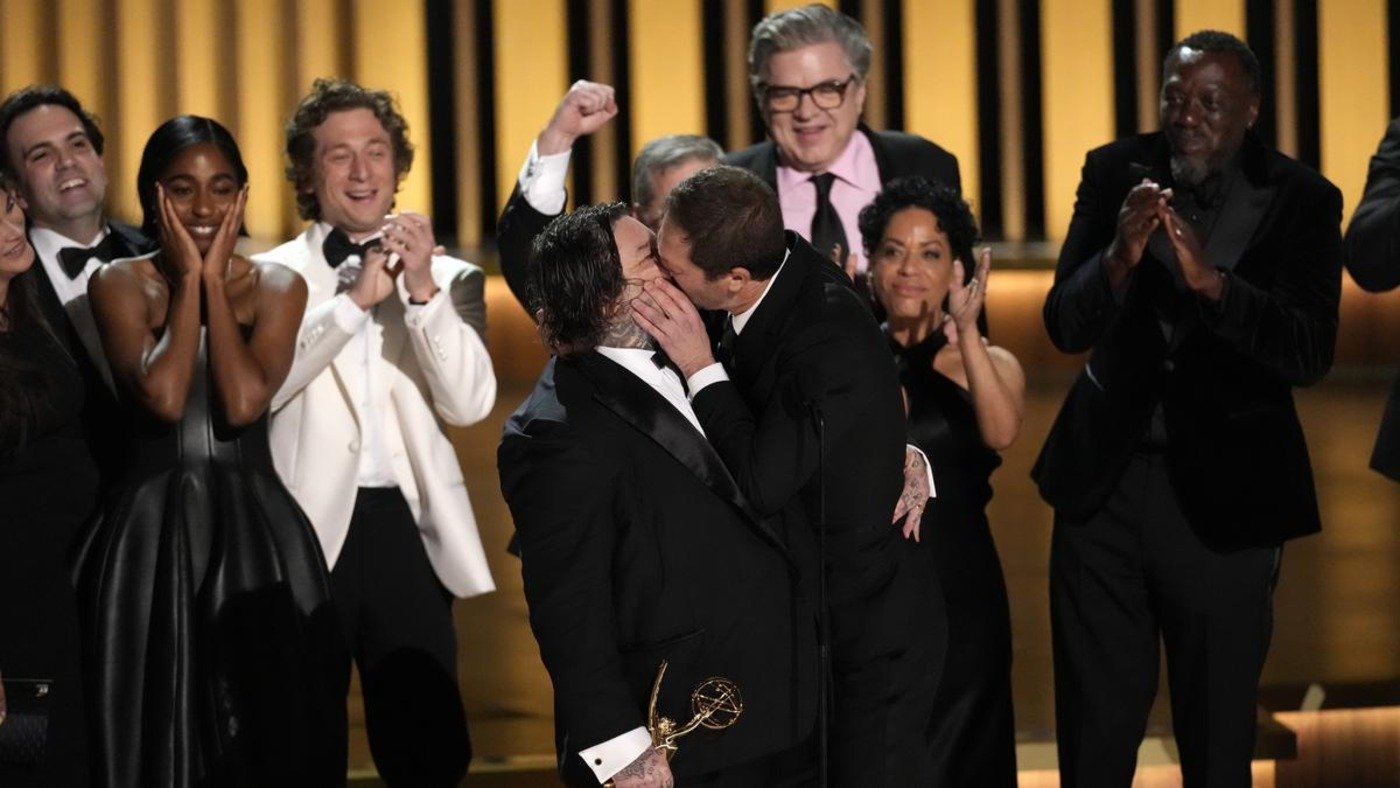 Matty Matheson, center, and Ebon Moss-Bachrach kiss as ‘The Bear’ wins the award for outstanding comedy series during the 75th Primetime Emmy Awards on Monday, Jan. 15, 2024, at the Peacock Theater in Los Angeles. | Photo Credit: Chris Pizzello