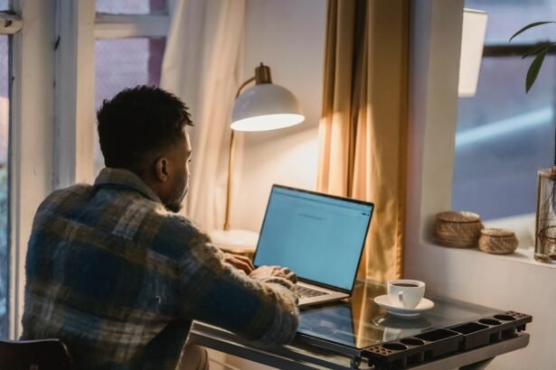 focused black man using laptop in evening at home